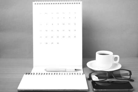 coffee,phone,eyeglasses,notepad and canlendar on wood table background black and white colorの写真素材