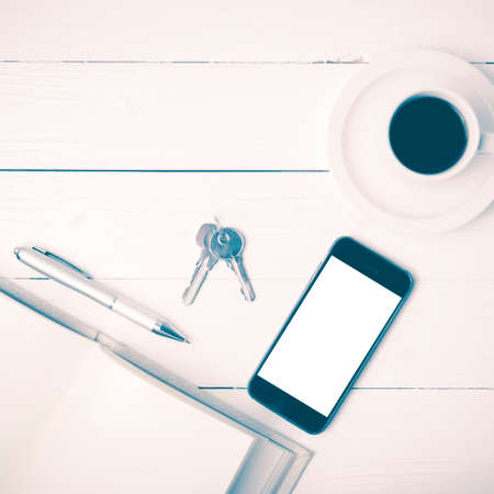 coffee cup with phone, key and open notebook on white wood table vintage styleの写真素材