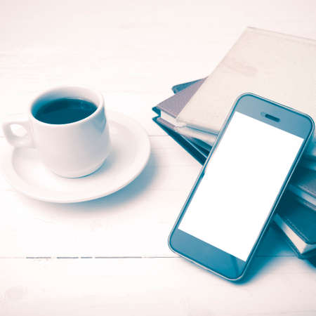 coffee cup with phone and stack of book on white wood table vintage styleの写真素材