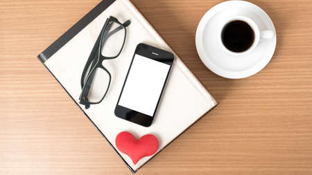 coffee,phone,eyeglasses,stack of book and heart on wood table background