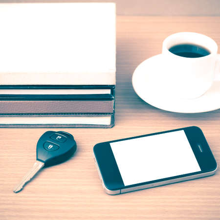 coffee cup with phone car key and stack of book on wood background vintage styleの写真素材