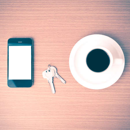 coffee cup and phone and key on wood background vintage styleの写真素材