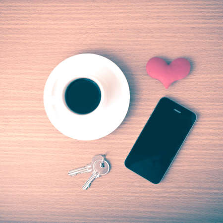 coffee phone key and heart on wood table background vintage style