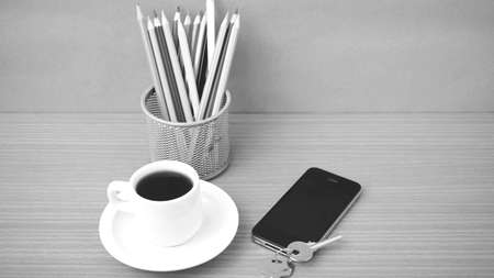 coffee,phone,key and pencil on wood table background black and white color