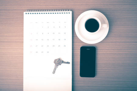 coffee,phone,key and calendar on wood table background vintage styleの写真素材