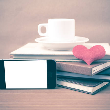 coffee,phone,stack of book and heart on wood table background vintage styleの写真素材