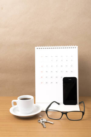 coffee,phone,eyeglasses,calendar and key on wood table backgroundの写真素材