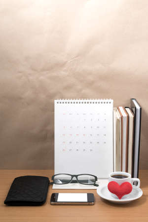 desktop : coffee with phone,stack of book,wallet,heart,eyeglasses,calendar on wood backgroundの写真素材
