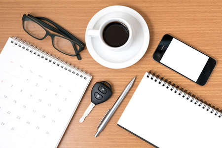 coffee and phone with car key,eyeglasses,notepad,calendar on wood backgroundの写真素材