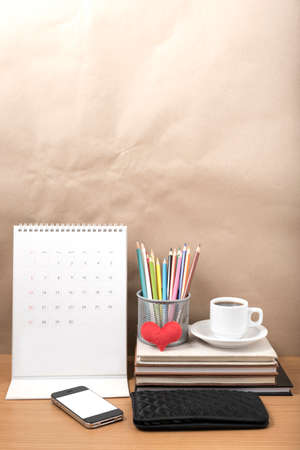 office desk : coffee with phone,wallet,calendar,heart,color pencil box,stack of book,heart on wood backgroundの写真素材