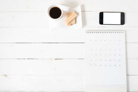 coffee cup with wafer,phone,calendar on white wood backgroundの写真素材