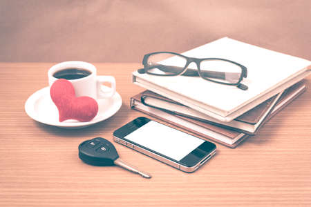 office desk : coffee and phone with car key,eyeglasses,stack of book,heart vintage styleの写真素材