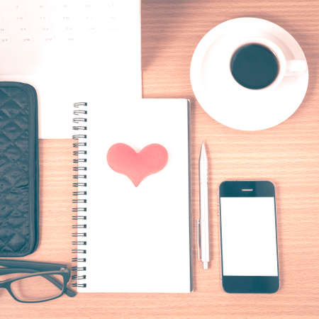 office desk : coffee with phone,wallet,calendar,heart,notepad,eyeglasses,heart on wood background vintage styleの写真素材
