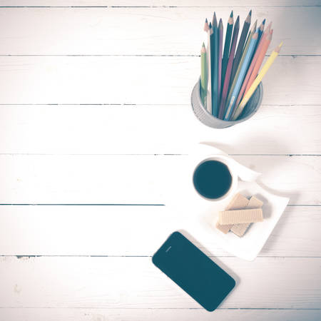 coffee cup with wafer,phone,pencil box on white wood background vintage styleの写真素材