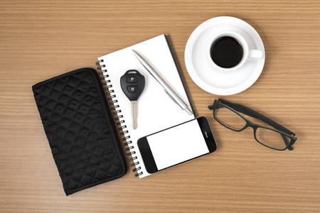 coffee and phone with notepad,car key,eyeglasses and wallet on wood table backgroundの写真素材