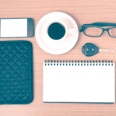 coffee and phone with notepad,car key,eyeglasses and wallet on wood table background vintage styleの写真素材