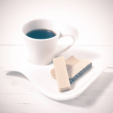 coffee cup with wafer on white wood background vintage styleの写真素材