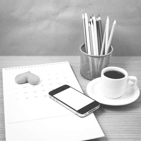 office desk : coffee with phone,calendar,heart on wood background black and white colorの写真素材