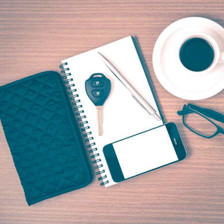 coffee and phone with notepad,car key,eyeglasses and wallet on wood table background vintage styleの写真素材