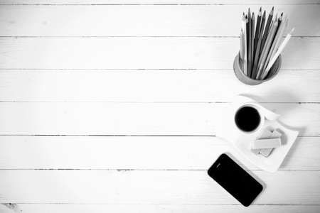 coffee cup with wafer,phone,pencil box on white wood background black and white colorの写真素材