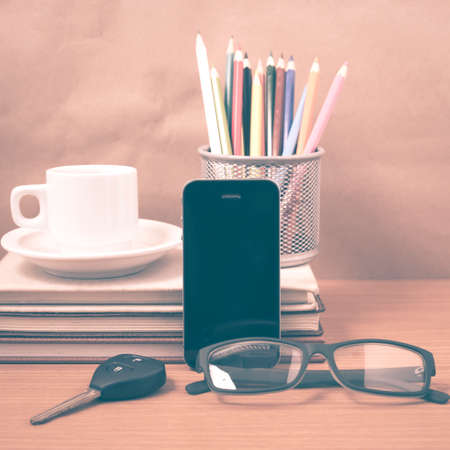 office desk : coffee and phone with car key,eyeglasses,stack of book,pencil box vintage styleの写真素材