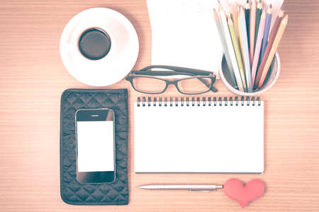 office desk : coffee with phone,wallet,calendar,color pencil box,notepad,heart on wood background vintage styleの写真素材
