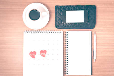 office desk : coffee with phone,wallet,calendar,heart,notepad on wood background vintage styleの写真素材