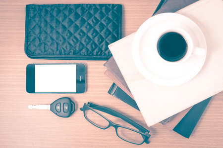 coffee and phone with stack of book,car key,eyeglasses and wallet on wood background vintage style