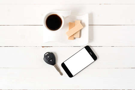 coffee cup with wafer,phone,car key on white wood background