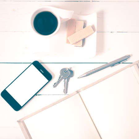 coffee cup with wafer,phone,key,notebook on white wood background vintage styleの写真素材