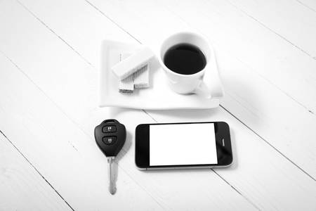 coffee cup with wafer,phone,car key on white wood background black and white colorの写真素材