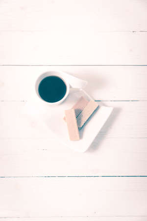 coffee cup with wafer on white wood background vintage styleの写真素材