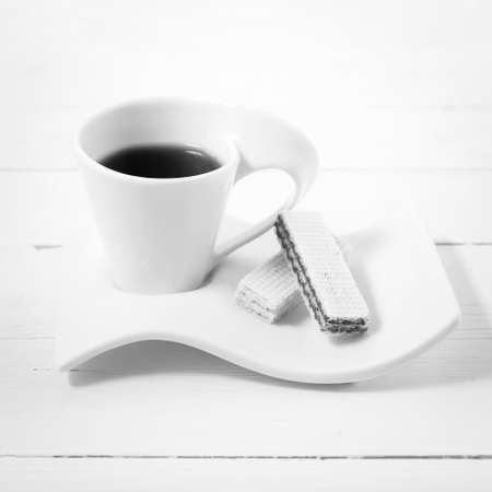 coffee cup with wafer on white wood background black and white colorの写真素材