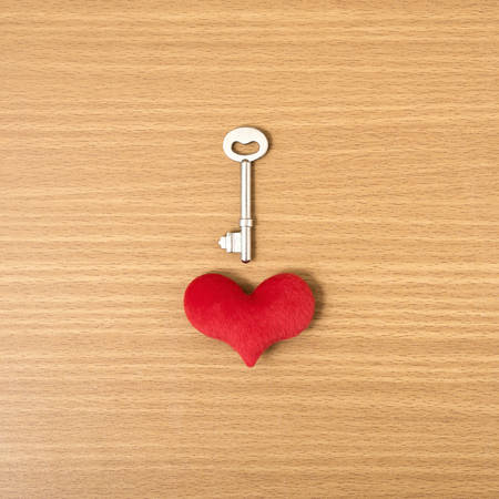 red heart with key on wood table background