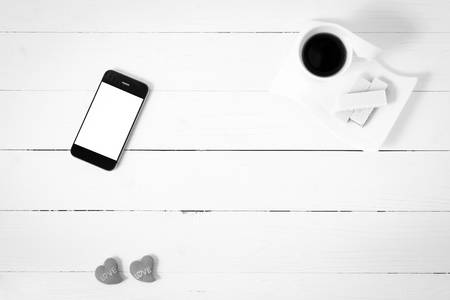 coffee cup with wafer,phone,heart on white wood background black and white color