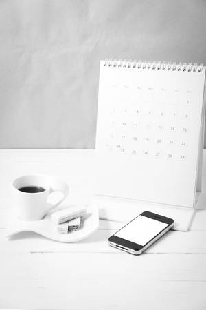 coffee cup with wafer,phone,calendar on white wood background black and white colorの写真素材