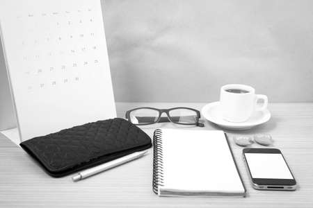 office desk : coffee with phone,wallet,calendar,heart,notepad,eyeglasses,heart on wood background black and white colorの写真素材