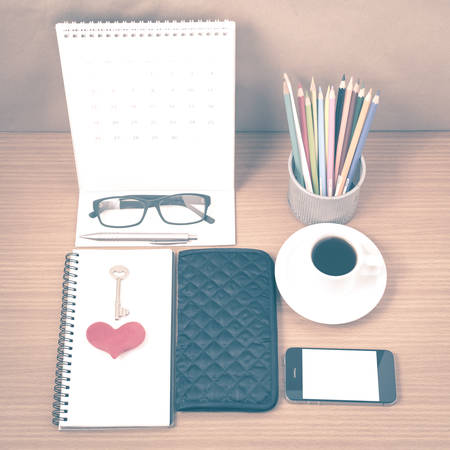 office desk : coffee with phone,wallet,calendar,heart,notepad,eyeglasses,color pencil box,key on wood background vintage styleの写真素材