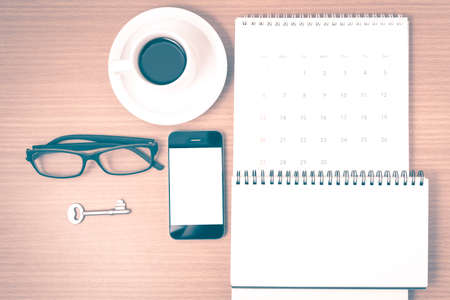 coffee and phone with key,eyeglasses,notepad,calendar on wood table background vintage styleの写真素材