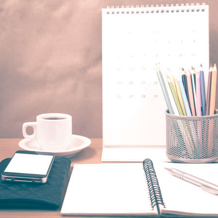 office desk : coffee with phone,wallet,calendar,color pencil box,notepad on wood background vintage...