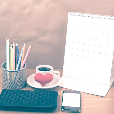 office desk : coffee with phone,wallet,calendar,heart,color pencil box on wood background vintage styleの写真素材