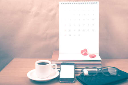 office desk : coffee with phone,stack of book,eyeglasses,wallet,calendar,heart on wood background  vintage styleの写真素材