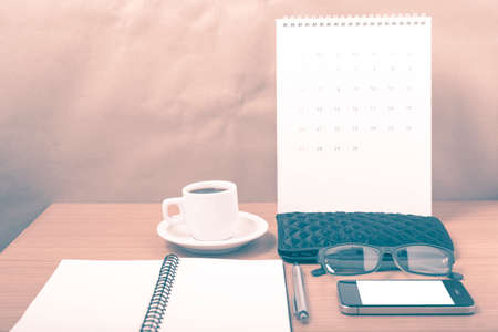 office desk : coffee with phone, calendar, wallet, notepad on wood background vintage styleの写真素材