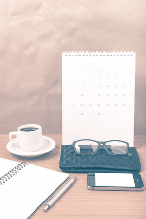 office desk : coffee with phone, calendar, wallet, notepad on wood background vintage styleの写真素材