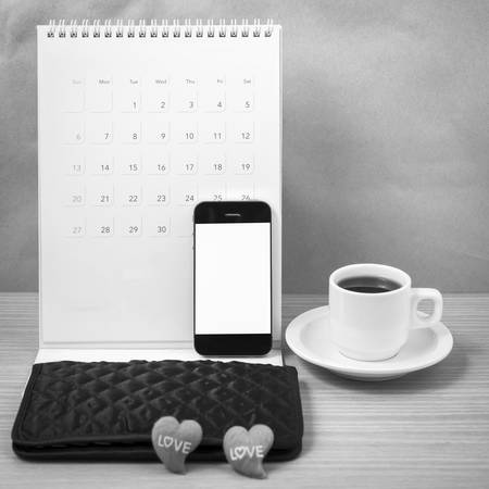 office desk : coffee with phone, calendar, wallet, heart on wood background black and white toneの写真素材