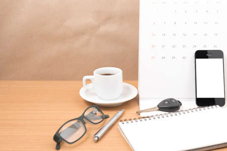 coffee and phone with car key, eyeglasses, notepad, calendar on wood backgroundの写真素材
