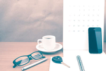 coffee and phone with car key, eyeglasses, notepad, calendar on wood background vintage styleの写真素材