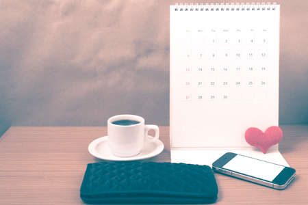 office desk : coffee with phone,wallet,calendar,heart on wood background vintage styleの写真素材