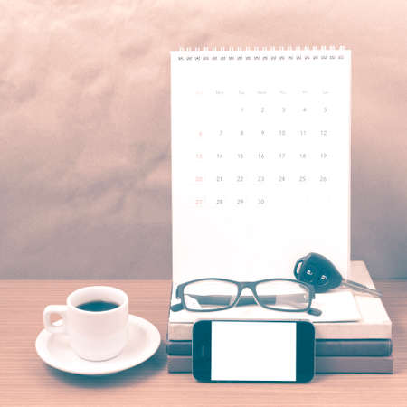 coffee and phone with car key,eyeglasses,stack of book,calendar on wood background vintage styleの写真素材