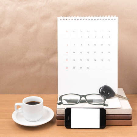 coffee and phone with car key,eyeglasses,stack of book,calendar on wood backgroundの写真素材